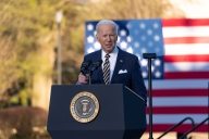 President Joe Biden stands at a podium with an American flag in the background.