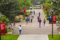 Students walk across the central thoroughfare of a college campus, University of St. Thomas Houston.